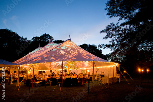 Wedding tent at night - Special event tent lit up from the inside with dark blue night time sky and trees photo