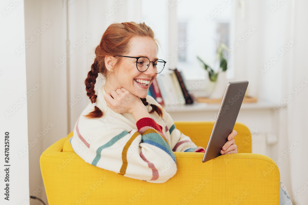 © contrastwerkstatt - Smiling happy young woman reading on a tablet