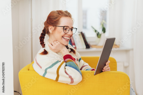 Smiling happy young woman reading on a tablet