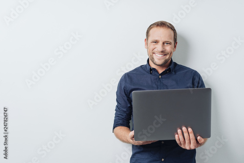 Attractive friendly man holding an open laptop