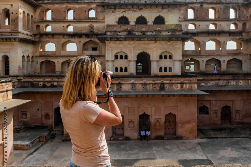 Young woman takes picture of Jahangir Mahal in Orchha, India