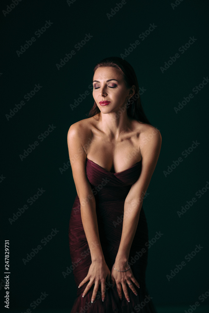 Portrait of magnificent sexy woman in evening dress posing over dark green background Portrait of magnificent sexy woman in evening dress posing over dark green background
