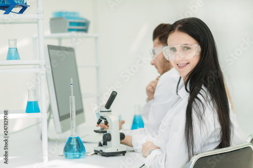 side view.female scientist sitting at a lab table