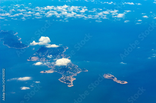 Aerial view landscape above Hong Kong islands from flying airplane. Sky, cloud and small ships at sea merged into one. Great background for travel