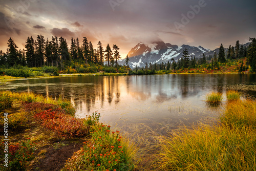 View from Picture lake of Mount Shuksan while the sunrise breaks through a incoming storm during the fall season.   photo