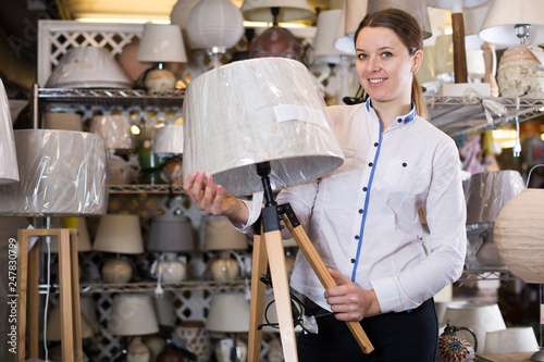Positive woman is standing with modern lamps
