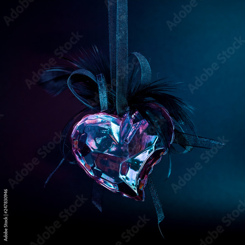 Glass, ice, heart on a dark background. Symbol of love and indifference photo