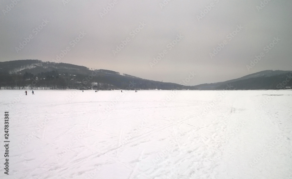Photo of a large frozen lake covered in snow Photo of a large frozen lake covered in snow