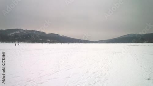 Photo of a large frozen lake covered in snow and surrounded by hills © Ji