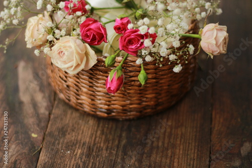 basket of pink roses wooden background