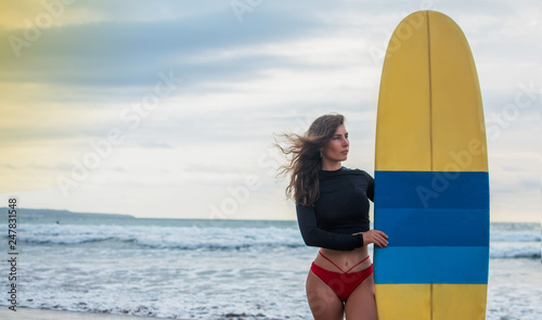 Photography Surfer woman going surfing standing with blue-yellow surfboard on Waikiki Beach