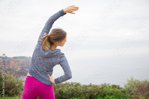 Photos Back view of sporty lady stretching body outdoors