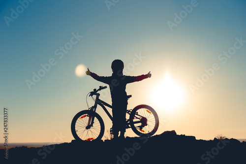 Silhouette of a little girl with a bicycle at sunset © bearok