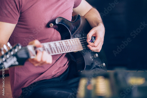 Close up hand of young man playing on a professional, black electric guitar, music instrument, entertainment (color toned image)