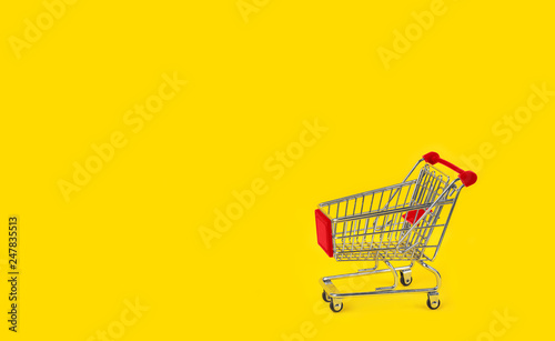 Shopping trolley on yellow background and some copy space.