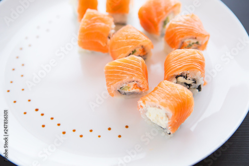 Sushi roll with salmon, philadelphia on a white plate, top view. Close-up. Beautifully decorated plate.