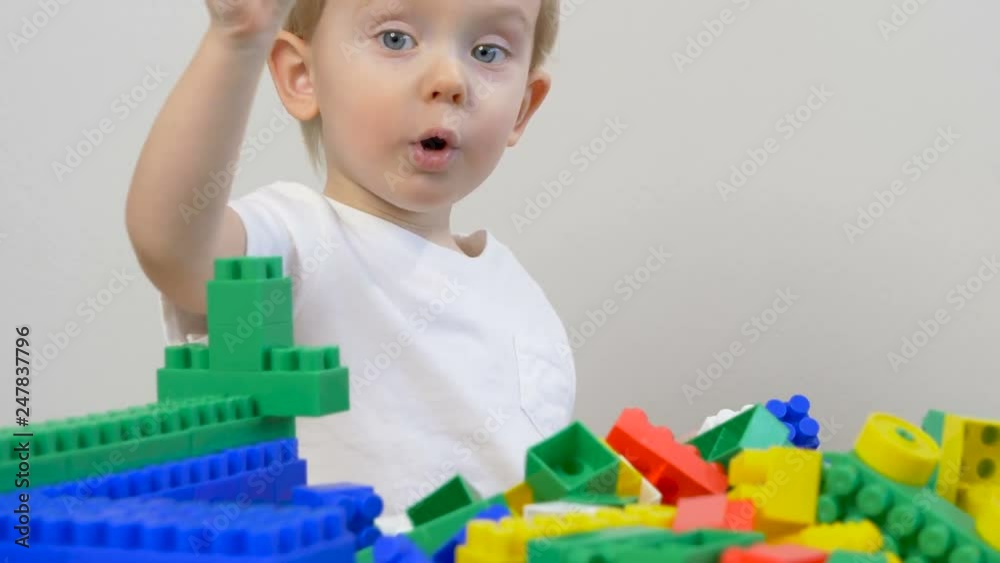 Cute little boy (toddler, two years old) is playing with Building bricks. Educational Building Blocks for babies kids. Early childhood education to children concept, kindergarten, pre-primary, nurser Cute little boy (toddler, two years old) is playing with Building bricks. Educational Building Blocks for babies kids. Early childhood education to children concept, kindergarten, pre-primary, nurser