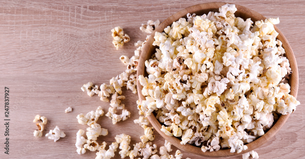 popcorn in a wood cup and on a wood table at a dark background popcorn in a wood cup and on a wood table at a dark background