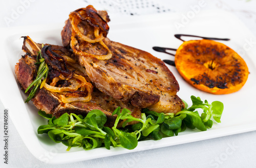Delicious fried pork chop with herb leaves, fried orange and onion