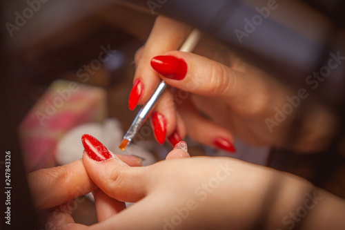 Manicure. Master make nail extension: drawing of white gel on free edge of a nail photo