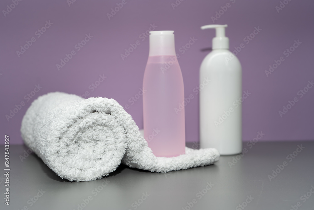 Cosmetic bottles and towel in pink and white colors