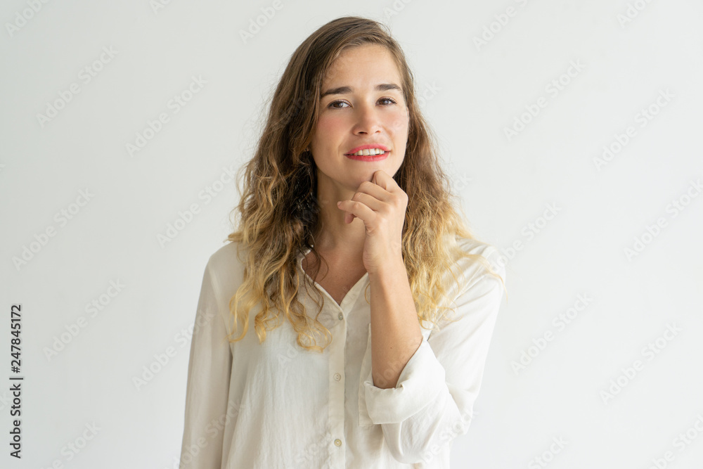 Smiling pretty young woman touching chin and looking at camera Smiling pretty young woman touching chin and looking at camera