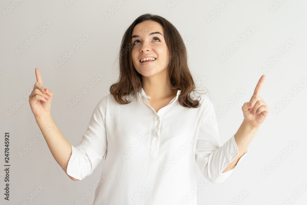 Smiling pretty young woman pointing and looking upwards Smiling pretty young woman pointing and looking upwards