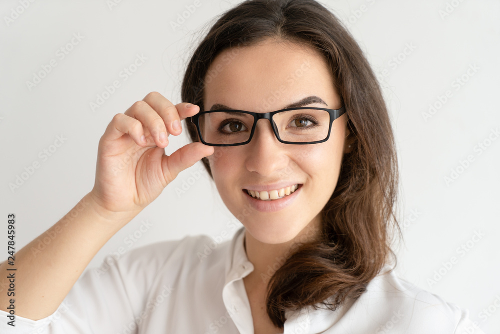 Smiling young woman adjusting glasses and looking at camera Smiling young woman adjusting glasses and looking at camera