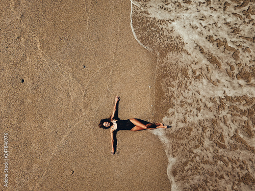 Canvas Print Aerial top view young woman lying on the sand beach and waves