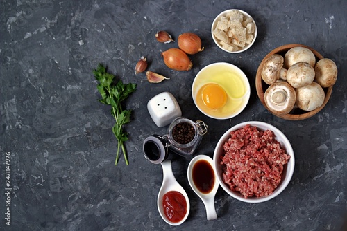 Ingredients for cooking meatloaf: minced meat, eggs, mushrooms, white bread, onion, garlic, tomato paste, soy sauce, salt, pepper. Top view, copy space.