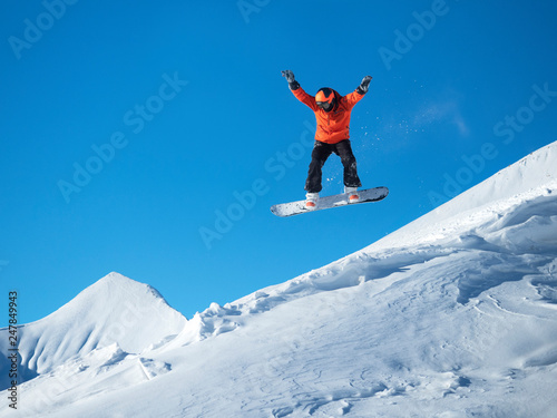 Snowboarder jump in the mountains against the blue sky