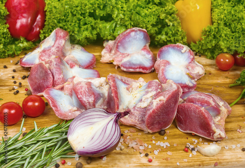 Chicken stomachs on a cutting wooden board with cherry tomatoes, lettuce leaves, garlic, chilli pepper, rosemary, onion, ready to be cooked photo