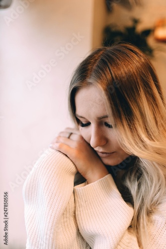 blonde girl in a cozy warm cafe, in a white knitted sweater 
