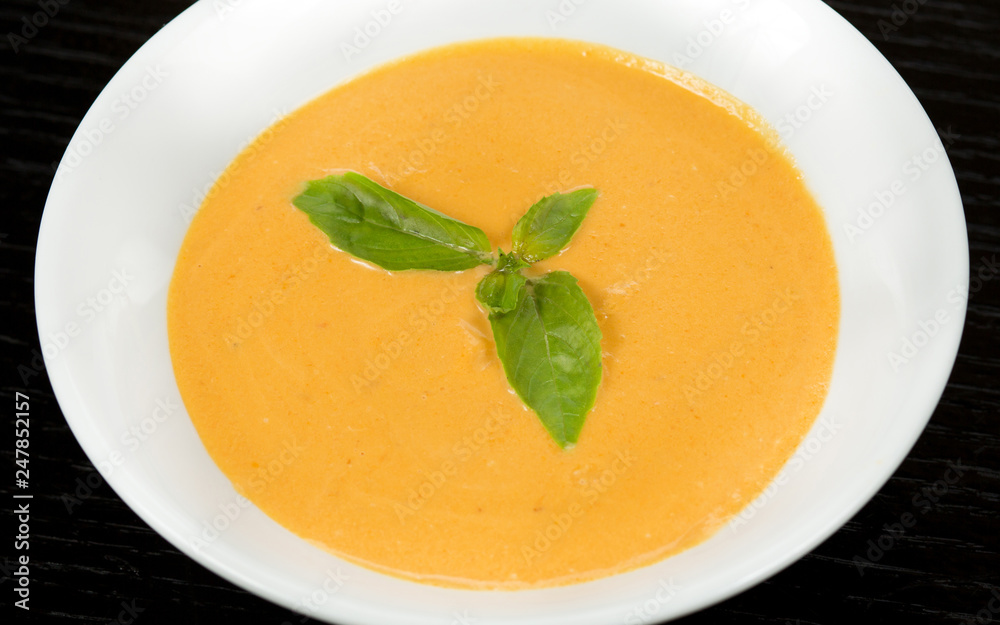 Pumpkin and carrot soup with cream and parsley on a dark wooden background Pumpkin and carrot soup with cream and parsley on a dark wooden background