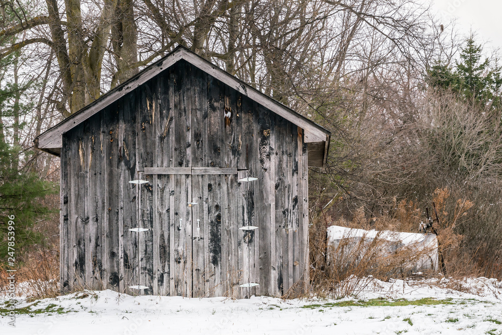 Small old weathered barn, farm building with fuel tank along side, winter, snow covered Small old weathered barn, farm building with fuel tank along side, winter, snow covered
