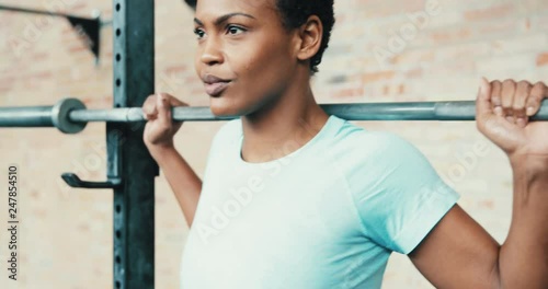 Focused young African American woman lifting weights at a gym photo