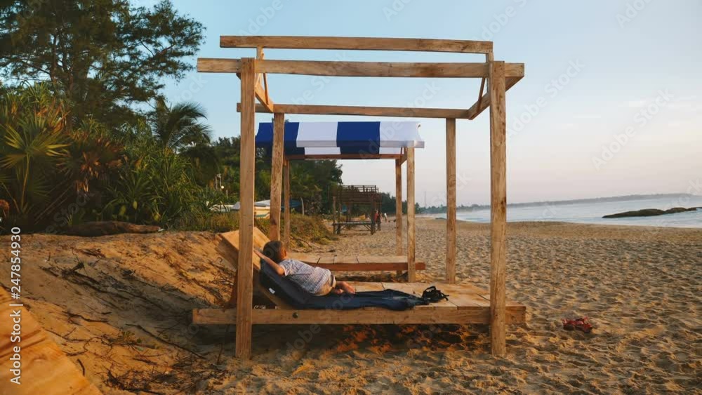 Beautiful shot of happy little relaxed boy child sleeping in beach lounge chair near sunset ocean waves on exotic shore. Beautiful shot of happy little relaxed boy child sleeping in beach lounge chair near sunset ocean waves on exotic shore.