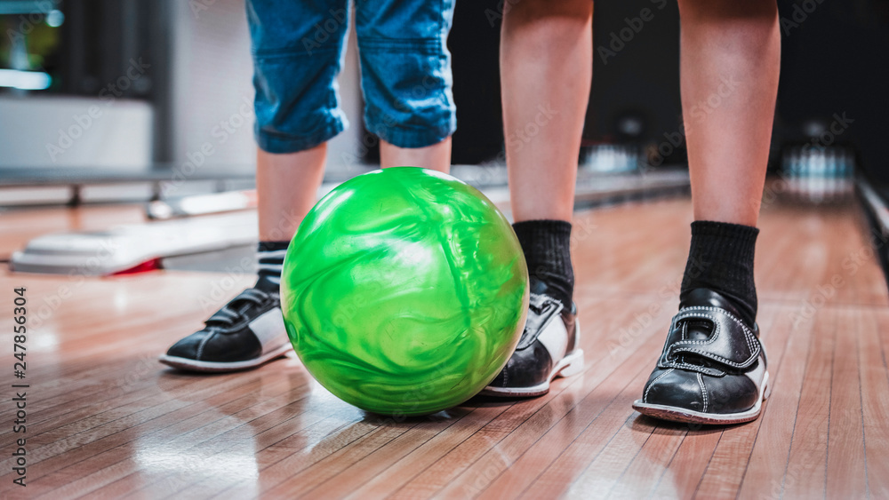 Photo kids legs with green bowling ball in a bowling alley. Stock-foto | Stock