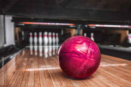 Pink bowling ball on bowling alley track.