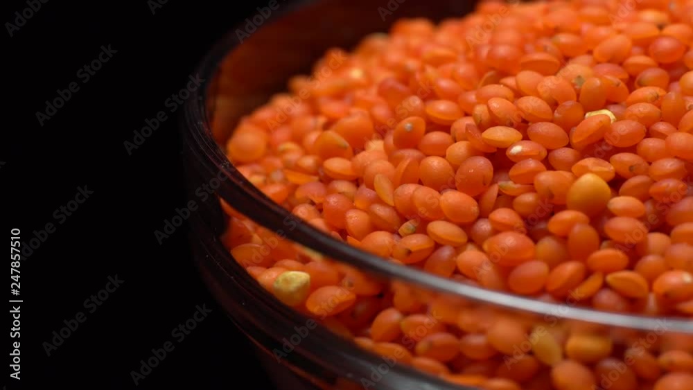 Lentils. Heap of raw uncooked red lentils in bowl in rotation. Red Chief Lentils, petite crimson lentils - Close up. Food background. black background, studio shot. Healthy organic food diet concept Lentils. Heap of raw uncooked red lentils in bowl in rotation. Red Chief Lentils, petite crimson lentils - Close up. Food background. black background, studio shot. Healthy organic food diet concept