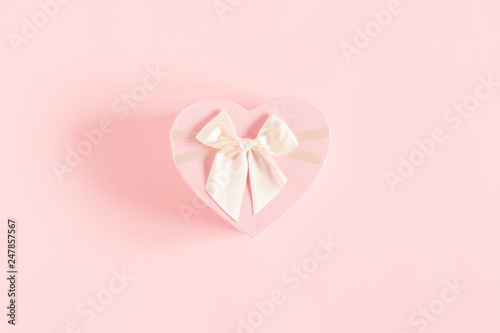 Gift with satin bow on light pastel pink background. Wedding. Birthday. Happy woman's day. Mothers Day. Valentine's Day. Minimal composition. Flat lay, top view