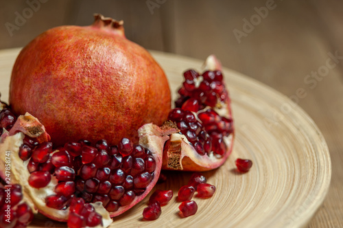 open pomegranate and flat plate on wooden table