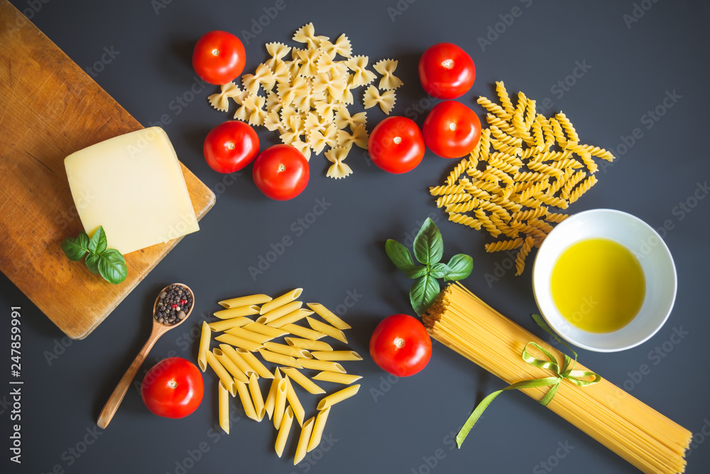 Different kinds of raw pasta and ingredients for cooking on dark background. Different kinds of raw pasta and ingredients for cooking on dark background.