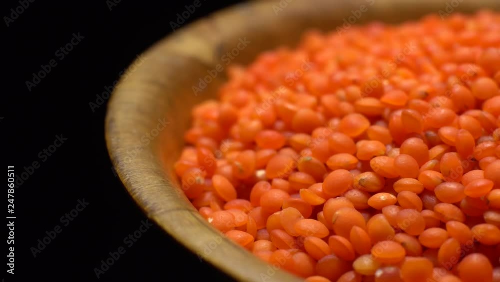 Lentils. Heap of raw uncooked red lentils in bowl in rotation. Red Chief Lentils, petite crimson lentils - Close up. Food background. black background, studio shot. Healthy organic food diet concept Lentils. Heap of raw uncooked red lentils in bowl in rotation. Red Chief Lentils, petite crimson lentils - Close up. Food background. black background, studio shot. Healthy organic food diet concept