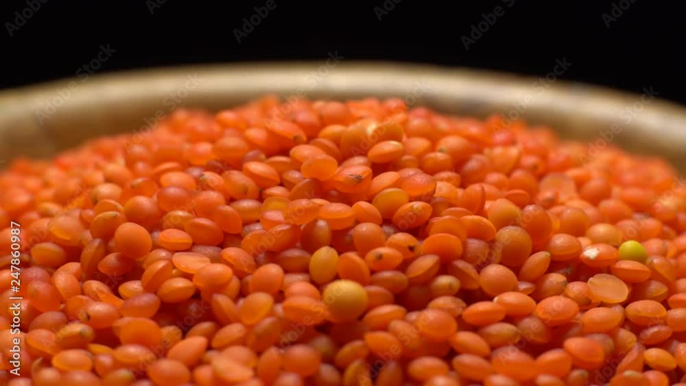 Lentils. Heap of raw uncooked red lentils in bowl in rotation. Red Chief Lentils, petite crimson lentils - Close up. Food background. black background, studio shot. Healthy organic food diet concept Lentils. Heap of raw uncooked red lentils in bowl in rotation. Red Chief Lentils, petite crimson lentils - Close up. Food background. black background, studio shot. Healthy organic food diet concept