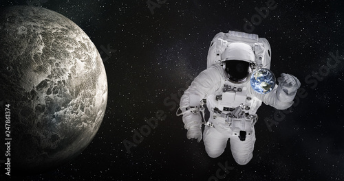 Single giant astronaut in outer space near tiny Earth and moonlike planet. Elements of this image were furnished by NASA.