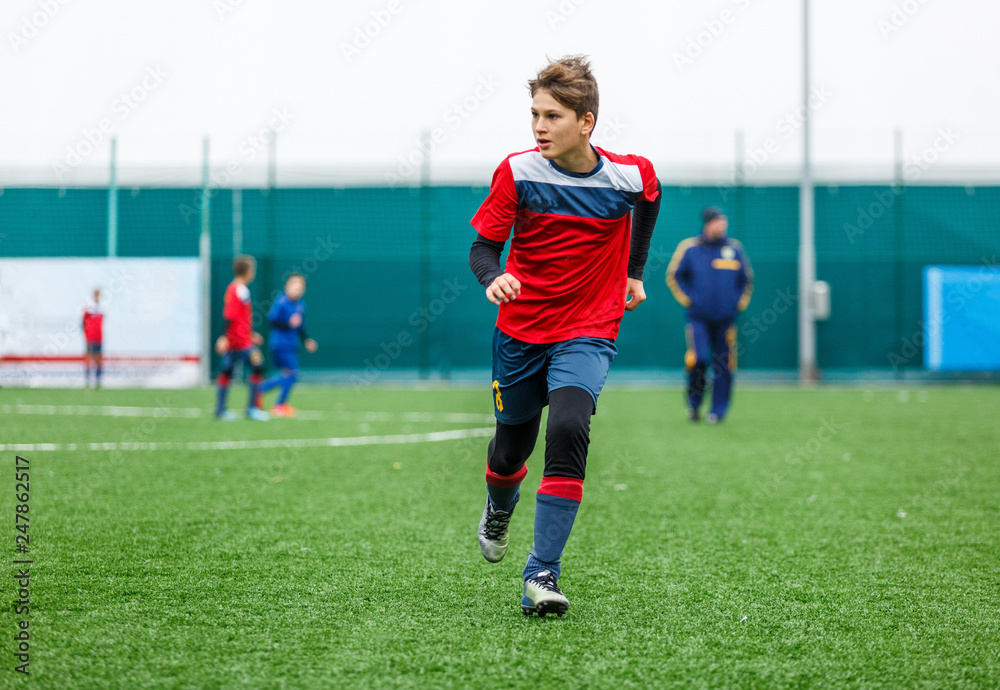 Boys in red white sportswear running on soccer field. Young footballers  dribble and kick football ball in game. Training, active lifestyle, sport,  children activity concept Stock Photo | Adobe Stock