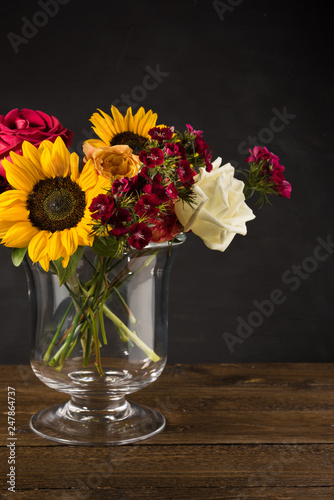 Bouquet of white yellow and red flowers in a vase on a dark background