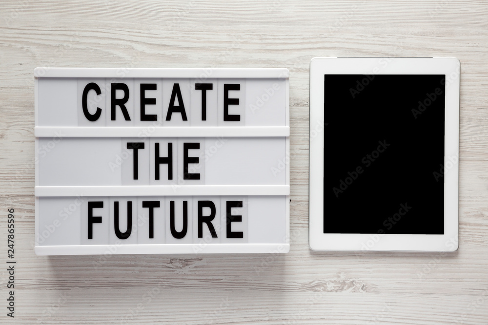 Modern board with text 'Create the future', tablet on a white wooden surface, top view. From above, flat lay, overhead. Modern board with text 'Create the future', tablet on a white wooden surface, top view. From above, flat lay, overhead.