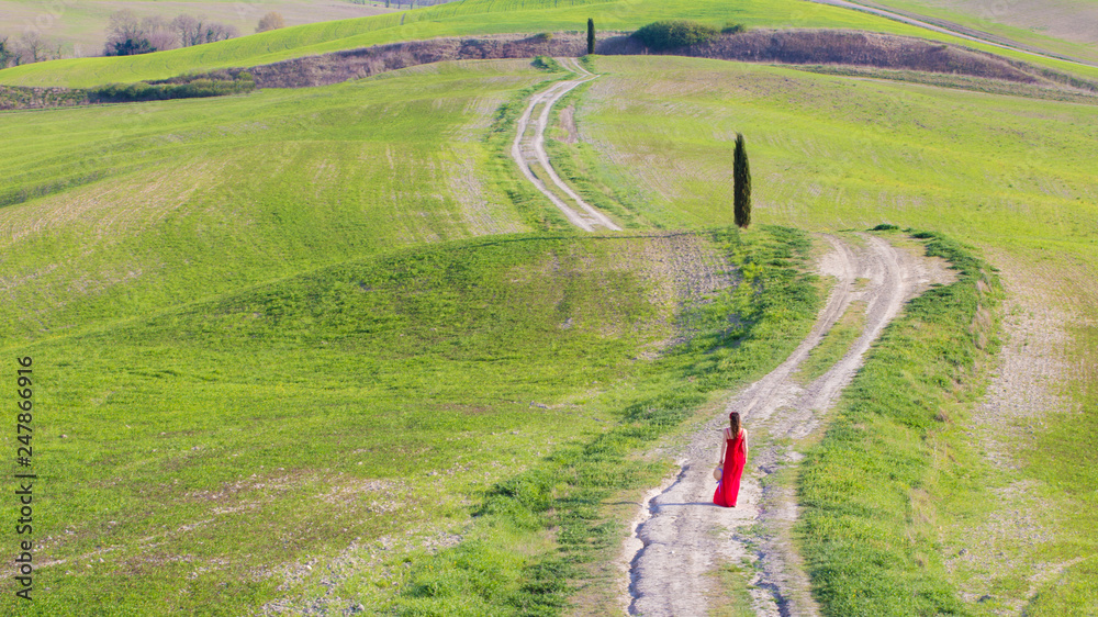 Ragazze vestia di rosso cammina in una strada tra le verdi colline